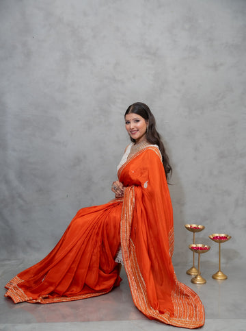 H.O. silk saree with golden striped border and kundan-style stone embroidery, available in red, orange, green, yellow, wine, and pink