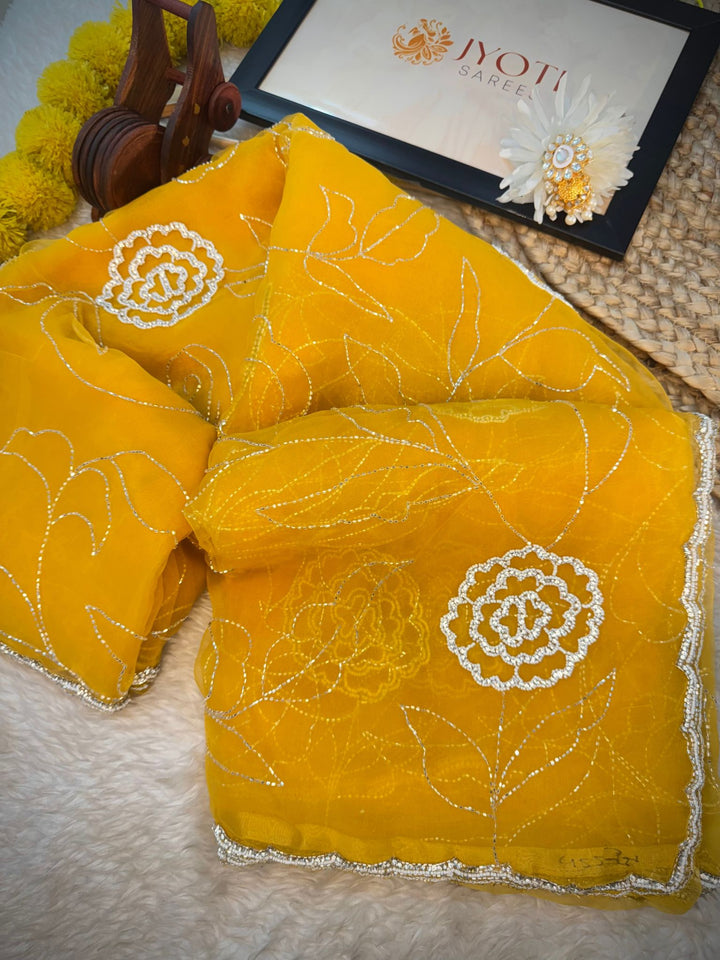 Glass tissue saree with floral embroidery in cutdana and pearl work, scalloped border, and unstitched blouse piece – by Jyoti Sarees